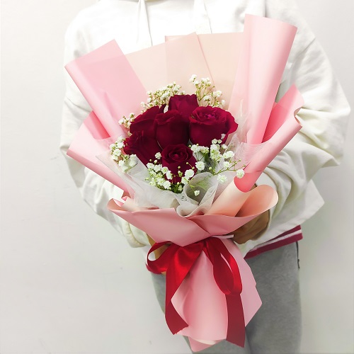 red roses in a pink hand bouquet
