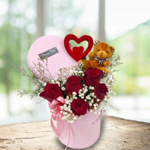 fresh red roses arranged in a box with a tiny bear and heart stick