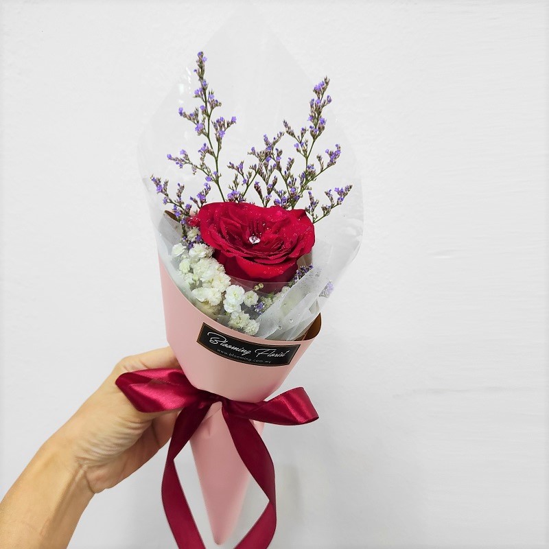 single red rose with diamond pin in a hand bouquet